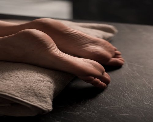 A person gently drying their feet with a soft white towel